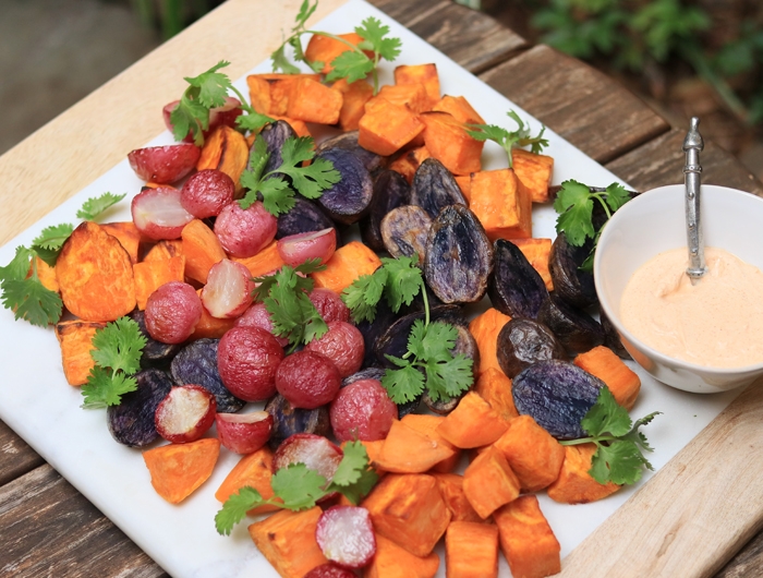 white platter filled with colorful root vegetables and side bowl of creamy sauce